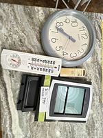 All items laid out: weather station display, outdoor sensor, wall clock, analog thermometer