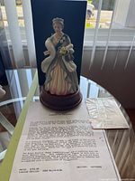 Full view of figurine on wooden base with paperwork visible