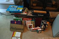 Overview of assorted board games stacked near fireplace, multiple classic board games visible in original boxes.
