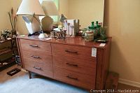 Photo of Kroehler dresser with six drawers, warm brown finish, tapered legs, and attached mirror behind with no frame. Various objects including lamps and decorative items on top of dresser.