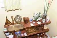 Overview of decor items on wooden shelves including brass decor, Delft blue mug, clock, ceramic items, and boxes.