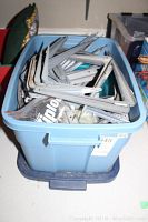 Blue bin filled with various metal L-shaped shelving brackets of different sizes and some mounting hardware.