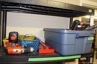 Shelf with various hand tools, Black and Decker cordless drill, storage bin and tool basket.