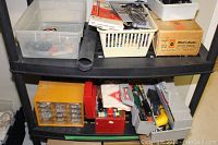 Two shelves with assorted hardware, tools, Black and Decker jigsaw in box, and parts organizers