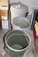 Photo showing the set of three garbage cans from the top view: tall plastic with lid, metal without lid, and plastic without lid, all with visible signs of use.