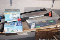 Two ice scrapers resting on top of a translucent plastic storage container with a lid, containing car mats and other items.