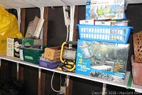 Shelving with various boxes and baskets holding tools and lighting equipment including flood lights, hand tools, a work light, and tool boxes.