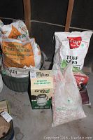 Photo showing all items grouped: Grab And Go sprayer box, bags of peat moss, turf seed, and landscape stone.