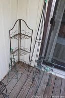 Full view of 4 metal garden decor pieces including corner shelf and 3 plant stands with decorative tops.