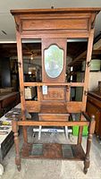Front view of oak hall stand showing mirror, hooks, drawer, umbrella rack and drip trays
