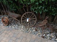 Overall view of three wheels, wheelbarrow pan, cultivator parts on stone ground