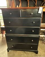 Front view showing black painted body, brown top, six drawers with metal knobs