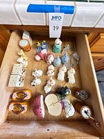 Drawer view showing majority of ceramic and glass novelty shakers and figurines