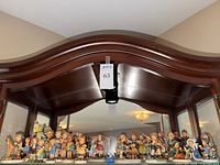 Upper cabinet shelf filled with assorted Goebel Hummel child figurines