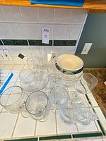 Group view of clear stemware, stacked Corelle bowls and plates, small saucers