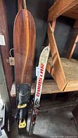 Side-by-side view of wooden Taperflex water ski and white Dynastar alpine ski with bindings
