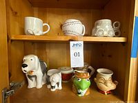 Two-shelf cabinet view showing all nine ceramic mugs