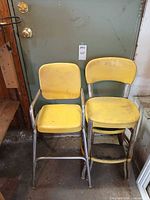 Front view of both yellow vinyl chairs showing overall design and condition