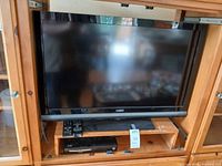 Front view showing Vizio TV, Blu-ray player and remotes in cabinet
