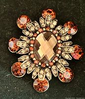 Front view showing amber oval center stone, surrounding brown and clear rhinestones