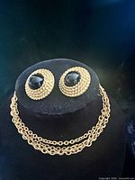 Necklace and earrings with black cabochons displayed on stand