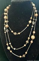 Full view of the multi-strand gold-tone necklace displayed on a bust
