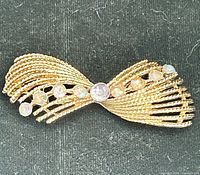 Front horizontal view showing gold-tone bow design and rhinestones