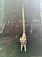 Front view of striped wooden cat figurine showing full height and long tail
