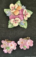 Front view of brooch and both earrings showing floral designs and colors