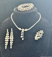 Full view of necklace, bracelet, earrings and brooch on display bust
