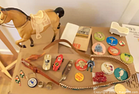 Group shot of entire lot on box: horse, belt, knife, race cars, pins, rings, cradle, armadillo, key ring, figure, coin visible
