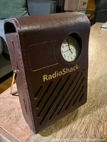 Front view of brown RadioShack AM/FM radio with watch chamber and speaker grille