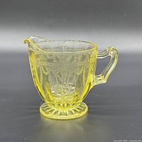 Full view of amber glass creamer showing Cameo pattern and pedestal base