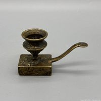 Side view of brass chamberstick showing candle cup, base and handle