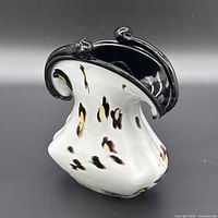 Front view of ruffled art glass vase showing flecked white body and black rim