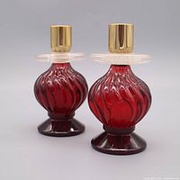 Front view of both red glass perfume bottle candlestick decanters showing overall design