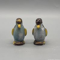 Front view of both penguin shakers showing glaze colors and dispensing holes