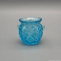 front view of blue pressed glass toothpick holder showing hobnail pattern and handles
