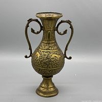 Front view of brass ewer showing handles, repousse decoration, pedestal base