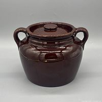Front view of brown stoneware bean pot with lid and handles