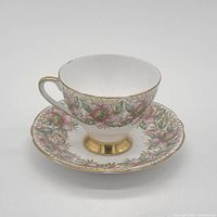 Front view of teacup on saucer showing floral pattern and gold trim
