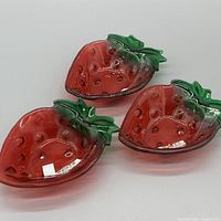 Three strawberry-shaped glass dishes displayed top view