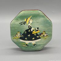 Top of tin showing green paint and lady illustration
