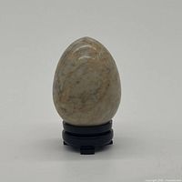 Front view of cream-beige marble egg with orange veining, displayed on a stand (stand not included)