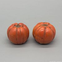 Front view of both orange cast iron pumpkin shakers