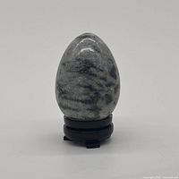 Front view of polished gray stone egg on temporary stand