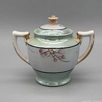 Front view showing luster glaze, floral design, gold handles, lid with finial