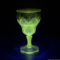 Goblet glowing bright green under UV light showing manganese content