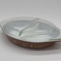 Side profile showing brown body, gold motif, and clear lid
