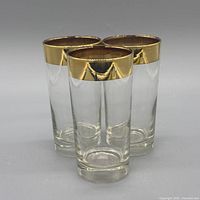 three glass tumblers grouped, showing gold rims and overall condition